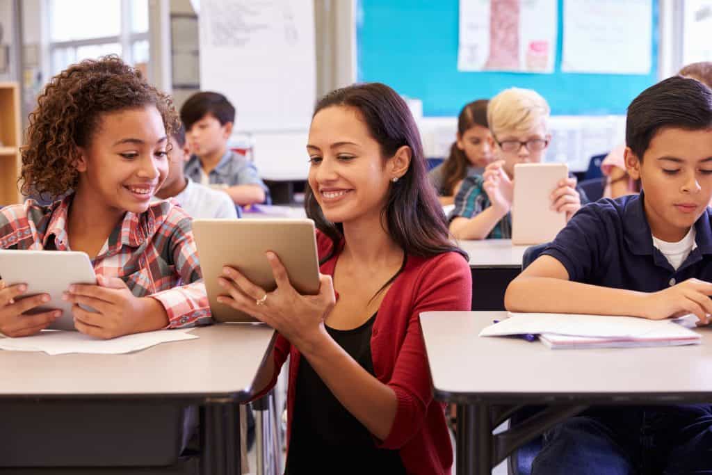 Happy teacher showing students lesson plan on tablet
